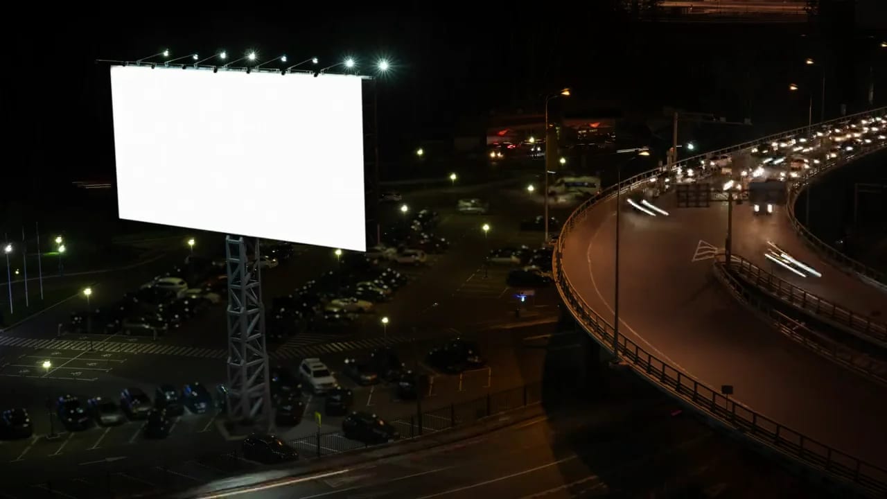 Gece otoyol kenarında aydınlatılmış boş billboard — outdoor reklam hizmeti